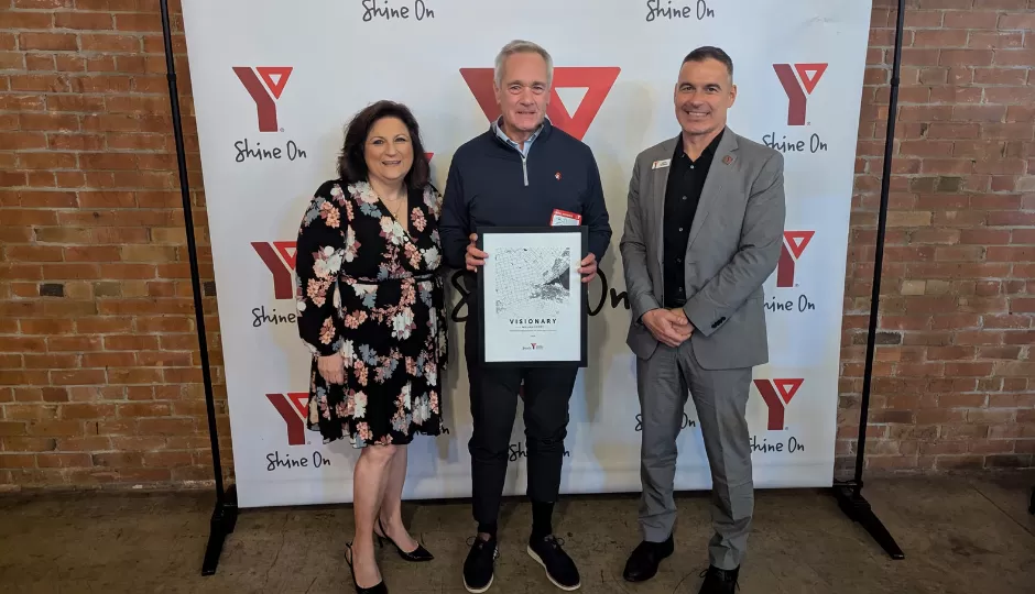 Manny, Nicki William verity in front of YMCA banner
