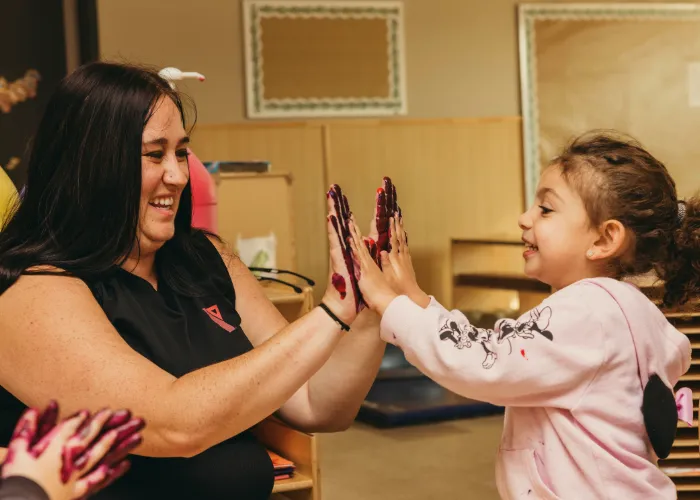 YMCA employee finger painting with child