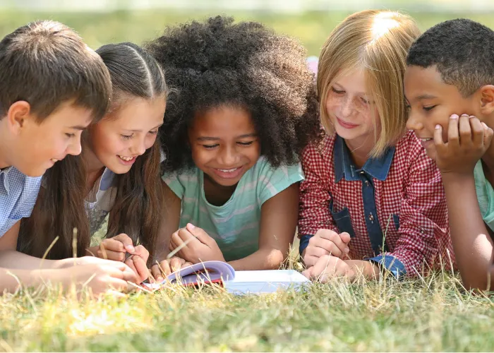 Kids laying in grass reading a book