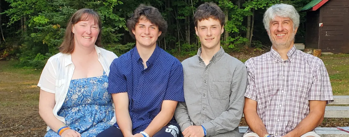 family sits on one side of picnic table and smiles for photo