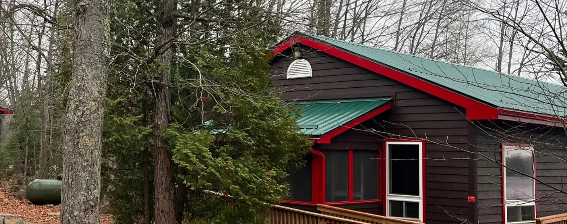 Brown cabins with forest green steel roofs and red trim