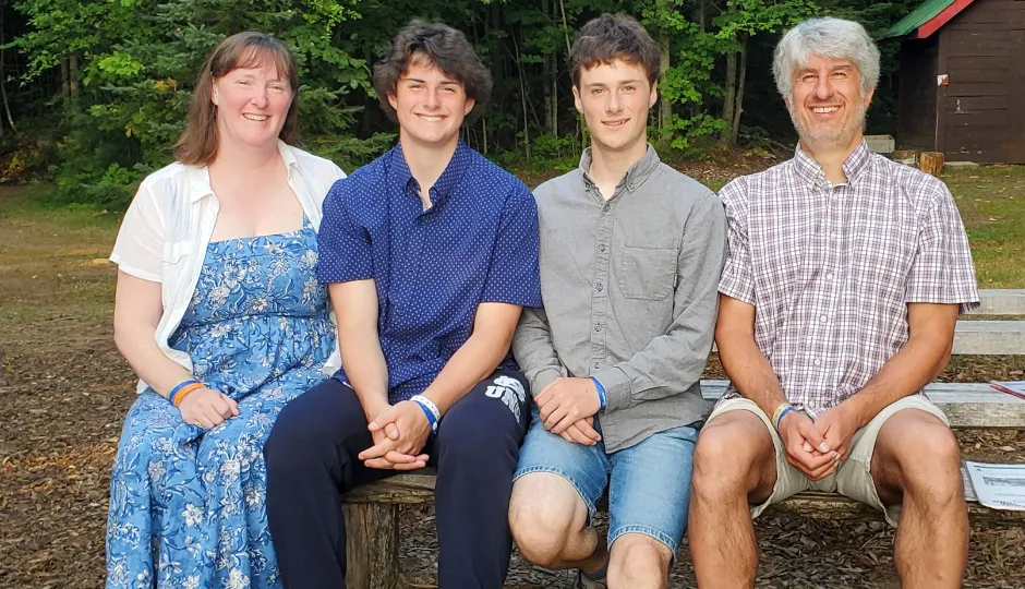 family sits on picnic bench smiling