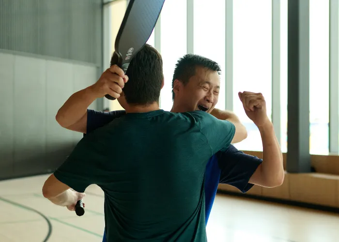 Two individuals celebrating over Pickelball