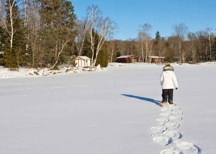 Snowshoer trekking across frozen lake
