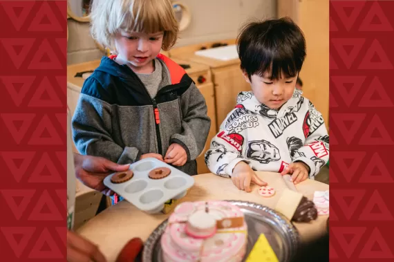 Two children making donuts at a table