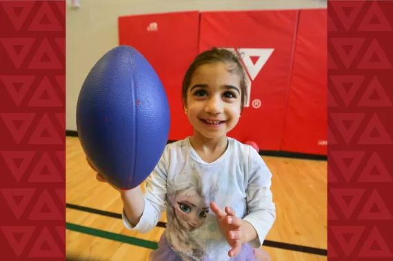 Girl holding foam football in a gym