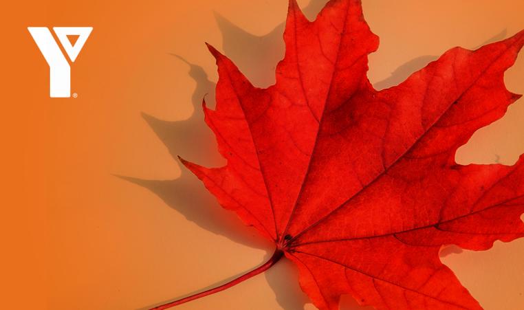 White YMCA logo with a red maple leaf on an orange background
