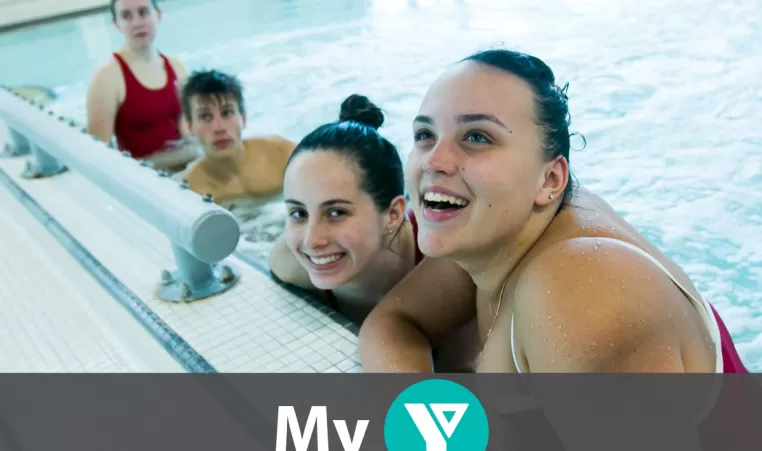 Three girls and one boy in a pool. The two girls who are closest to the camera are smiling.