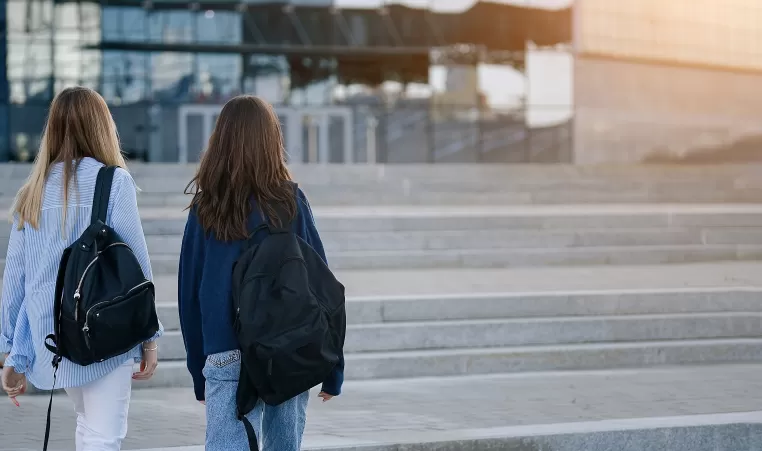 Two young people walking outside with backpacks