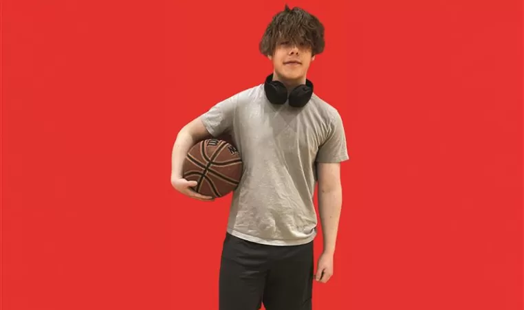 teenage boy holds basketball on red background