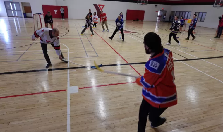 adults in gym playing floor hockey