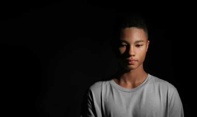 sad black youth with black background 