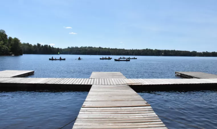 Swimming dock on lake with canoes in distance