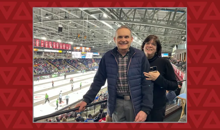Women stands behind man as they smile at camera in front of the Brier curling championship