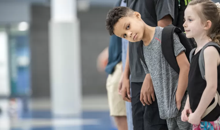 young boy leaning out of line