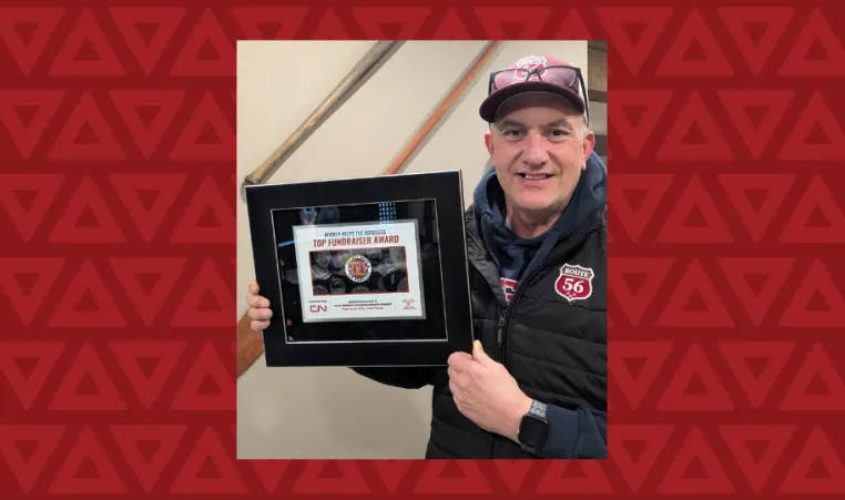 middle aged man holds award for top fundraiser