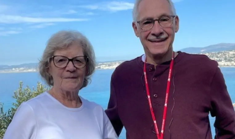 elderly couple stand in front of lake