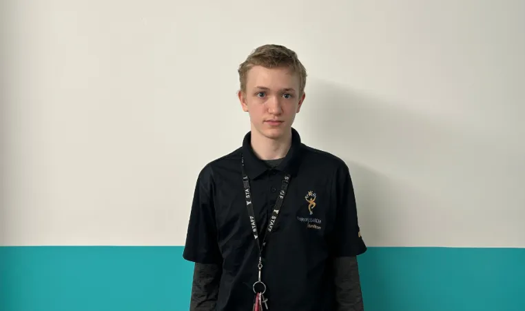 teenage boy stands in front of aqua wall