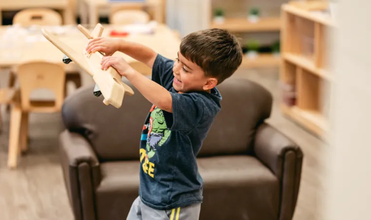 boy plays with wooden plane