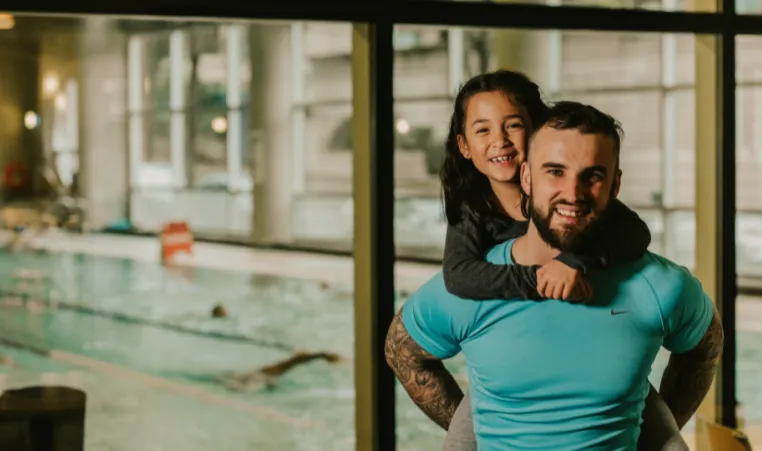 fatherg gives daughterpiggy back infront of pool