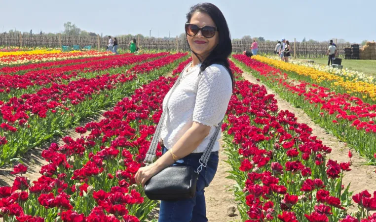 women stands in field of red tulips