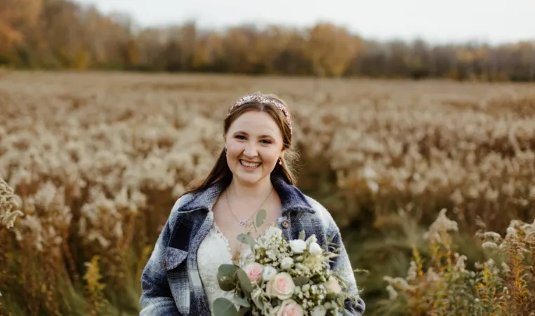bride in field wearing blue flannel