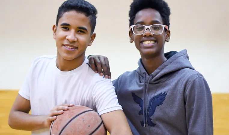 Two individuals smiling holding a basketball