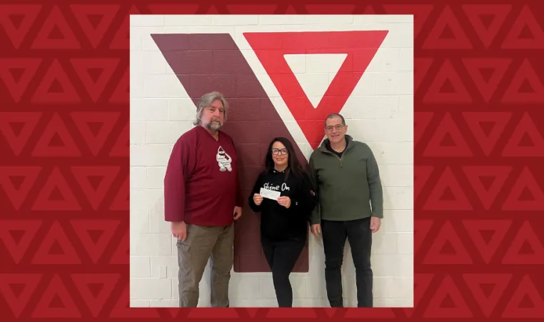 two men and one woman pose in front of YMCA logo