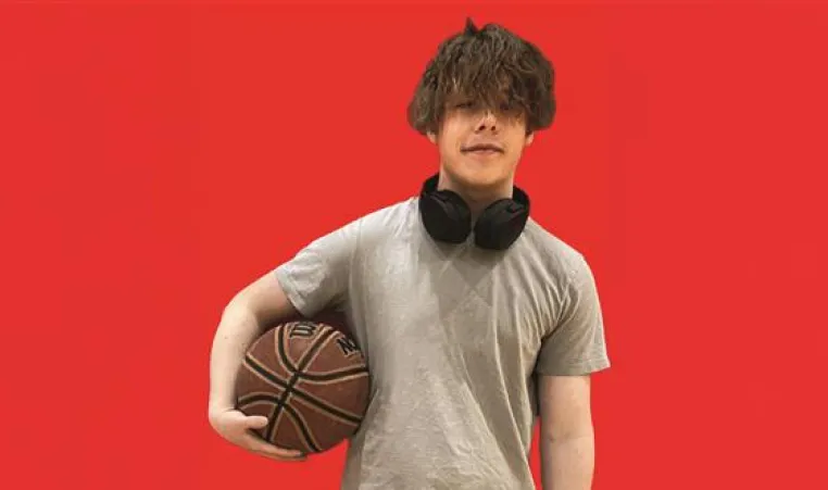 Teenage boy holding a basketball on a red background