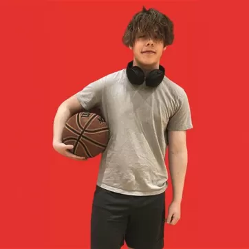teenage boy holds basketball on red background