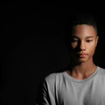 sad black youth with black background 