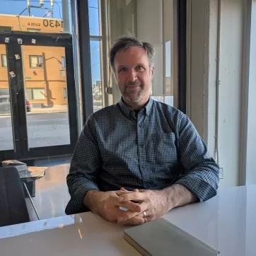 man sits with his hands crossed at a desk