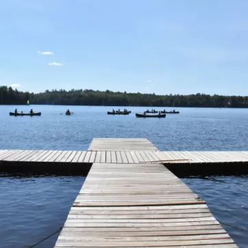 Swimming dock on lake with canoes in distance