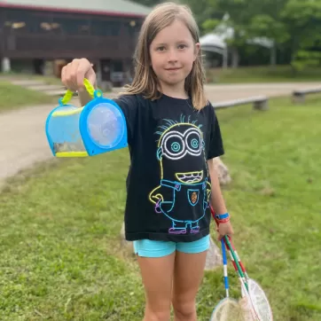 girl holding a bucket of bugs at a summer camp