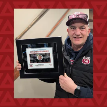 middle aged man holds award for top fundraiser