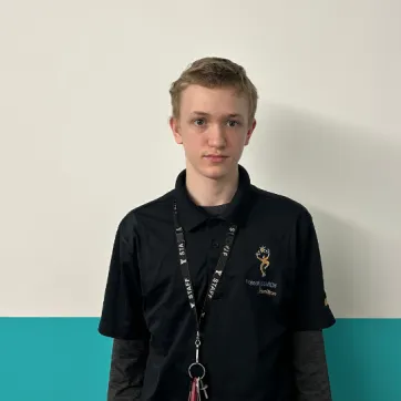 teenage boy stands in front of aqua wall