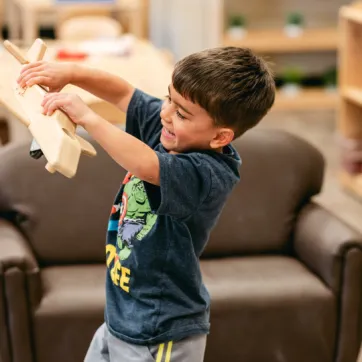 boy plays with wooden plane