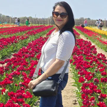 women stands in field of red tulips