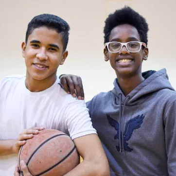 Two individuals smiling holding a basketball