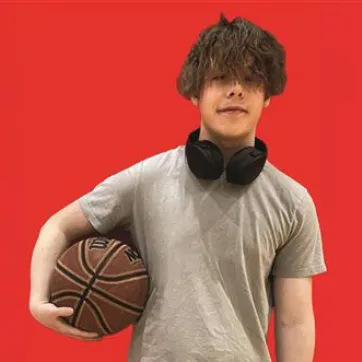 Teenage boy holding a basketball on a red background