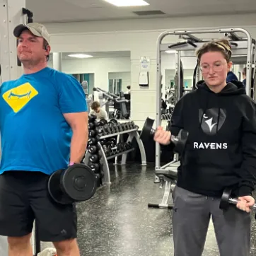 Father and daughter lift weights together in fitness centre