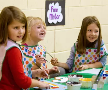 School age girls painting with paint brushes