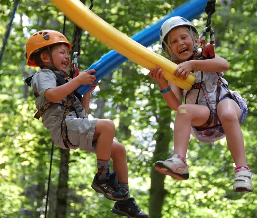 Laughing children hanging from high ropes