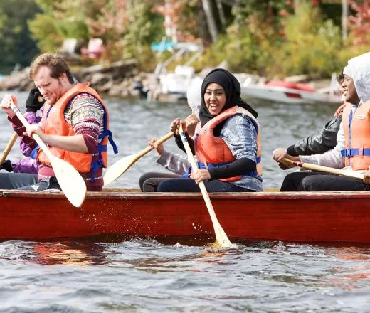 Smiling youth paddling in canoe on Koshlong Lake, Wanakita