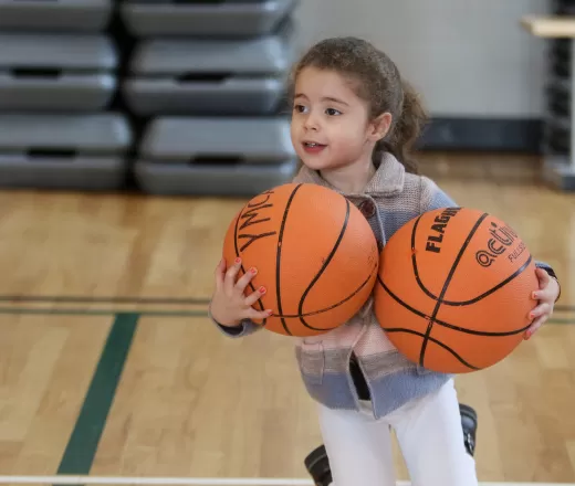 Female child holding two basketballs