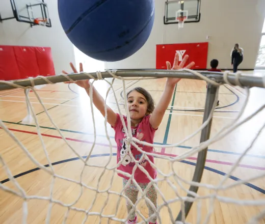Female child throwing basketball into net