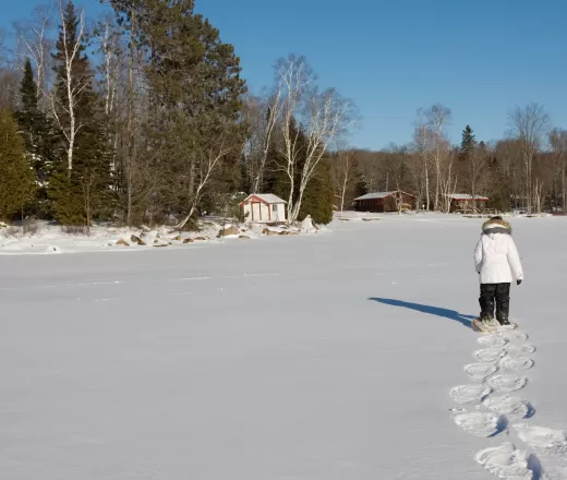 Snowshoer trekking across frozen lake