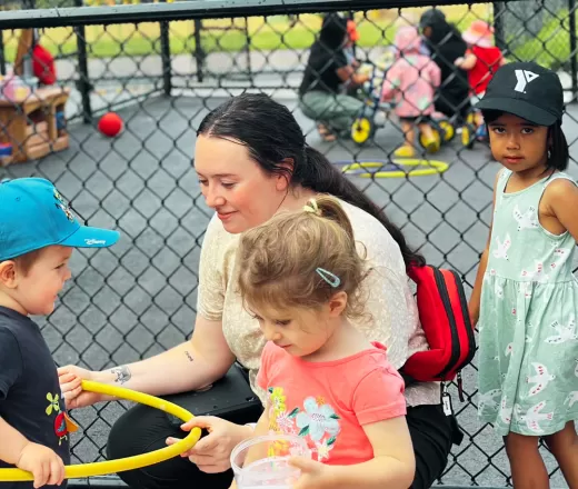 children playing outside with an educator at a YMCA Kinder Connections summer day program.
