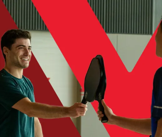 Two individuals playing pickelball