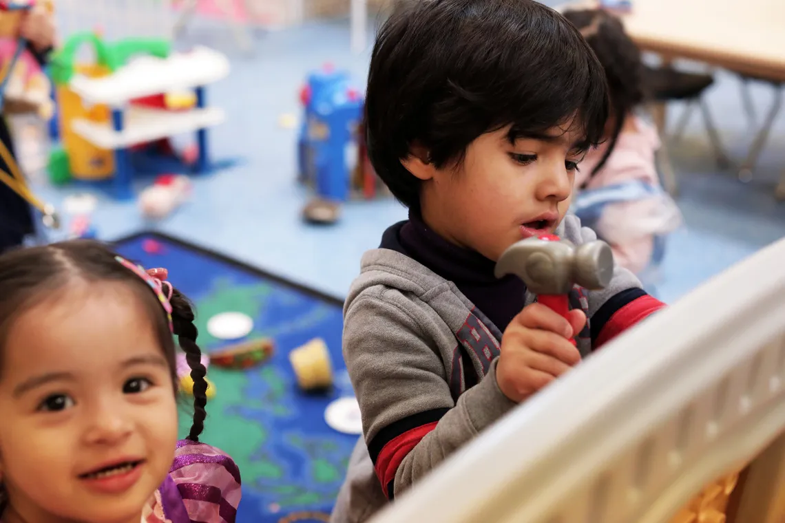 A male and female preschool child playing with toy hammer